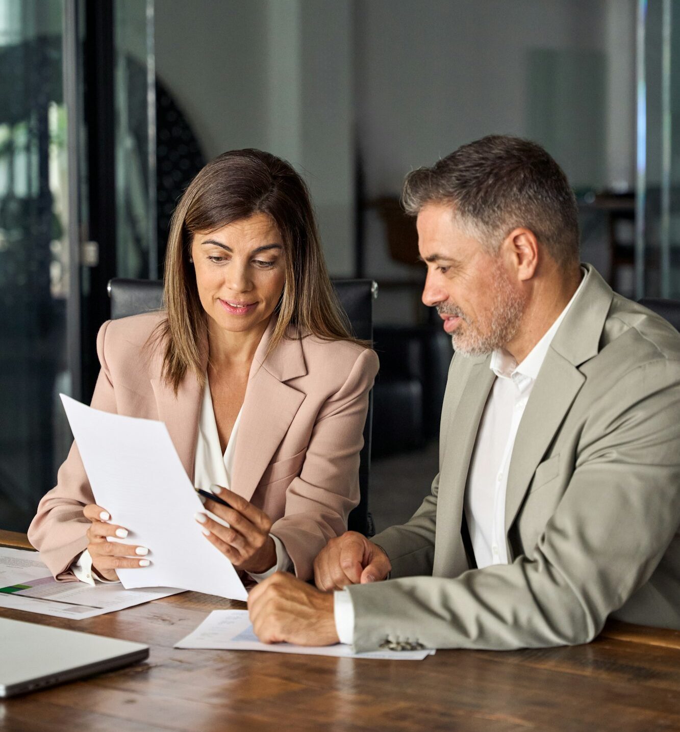 Female manager consulting client with documents at office meeting. Vertical.